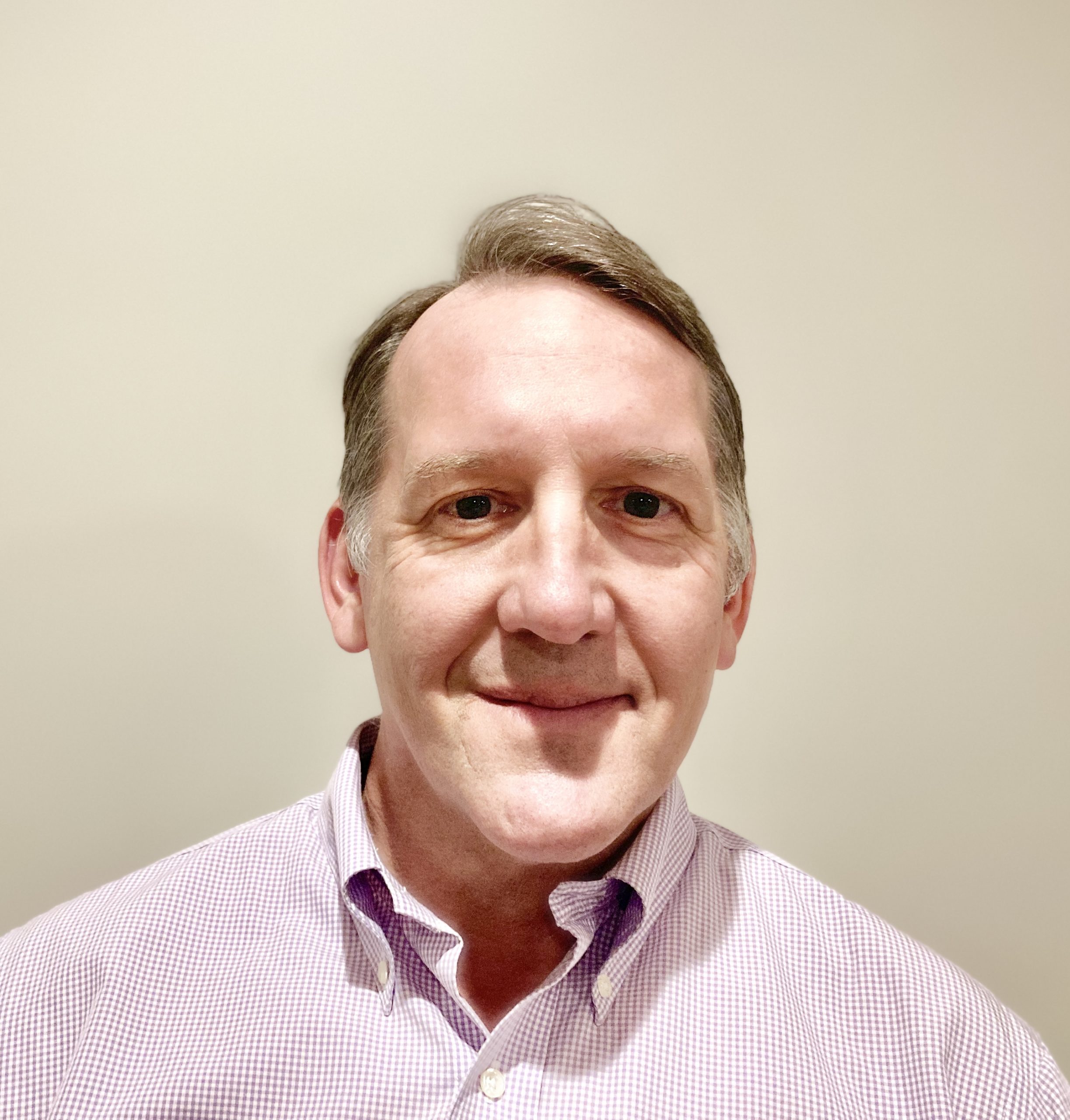 A man with short hair and a pink shirt.